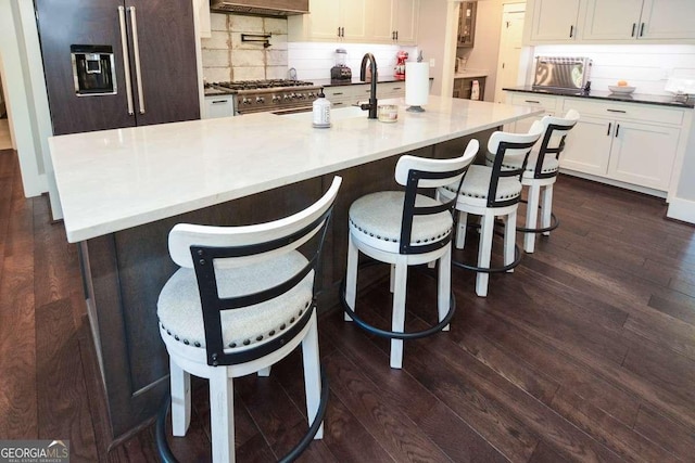 kitchen featuring white cabinetry, dark wood-style flooring, high quality appliances, and decorative backsplash