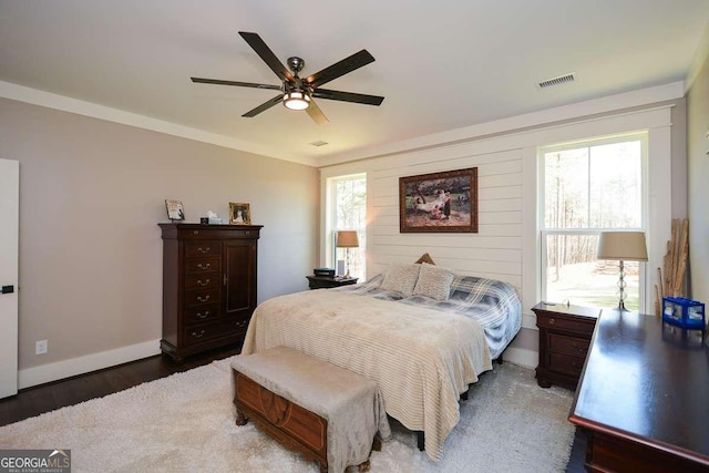 bedroom featuring ceiling fan, wood finished floors, visible vents, and baseboards