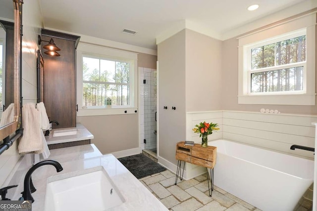 bathroom with double vanity, baseboards, visible vents, a soaking tub, and a sink