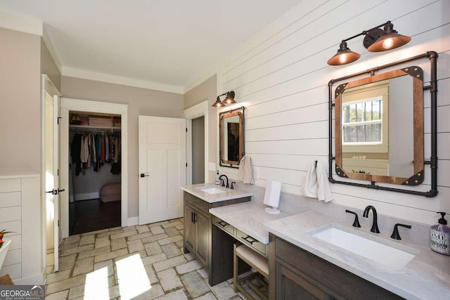 bathroom with ornamental molding, vanity, baseboards, and a spacious closet