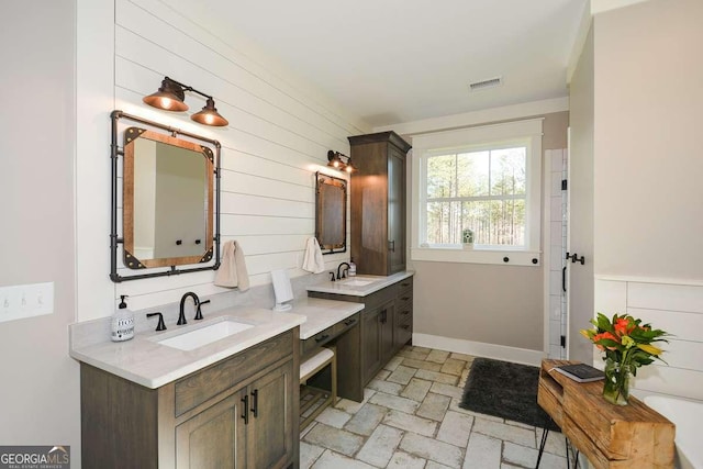 bathroom featuring stone finish floor, baseboards, visible vents, and vanity