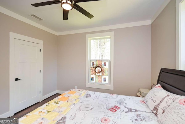 bedroom featuring baseboards, visible vents, dark wood finished floors, and ornamental molding