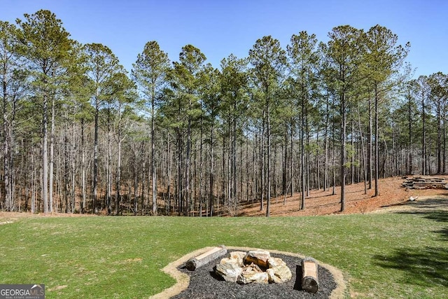 view of yard with a fire pit and a forest view