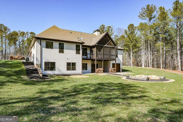 back of house featuring a sunroom, central AC, a lawn, and a chimney