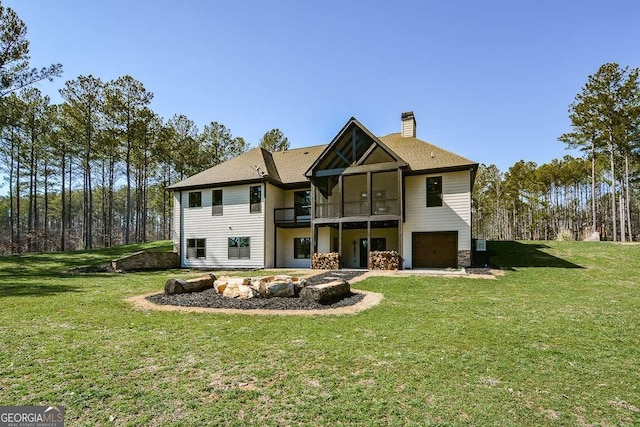 back of property featuring a garage, a patio area, a lawn, and a chimney