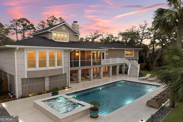 rear view of house with a patio, an in ground hot tub, stairway, a fenced in pool, and a chimney