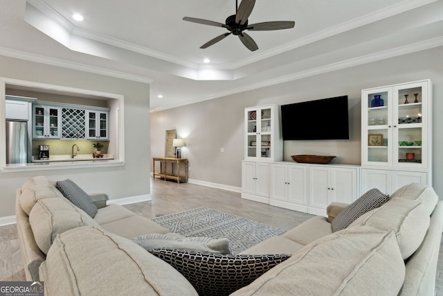 living room featuring baseboards, a raised ceiling, a ceiling fan, light wood-type flooring, and recessed lighting