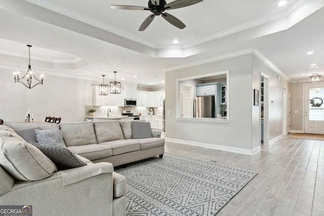 living area featuring a raised ceiling, light wood-style flooring, and baseboards