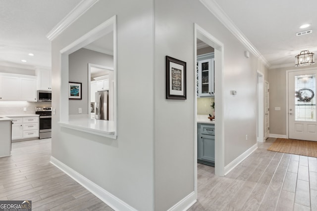 foyer featuring light wood-style floors, visible vents, and crown molding