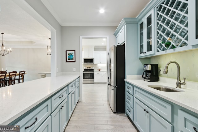 kitchen with stainless steel appliances, a notable chandelier, a sink, and ornamental molding