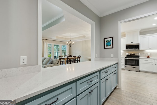 kitchen featuring light wood-style flooring, stainless steel appliances, white cabinetry, ornamental molding, and tasteful backsplash