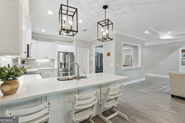 kitchen with tasteful backsplash, freestanding refrigerator, a peninsula, stainless steel refrigerator with ice dispenser, and a sink