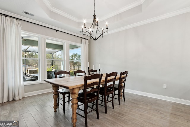 dining space with ornamental molding, wood finished floors, a raised ceiling, and baseboards