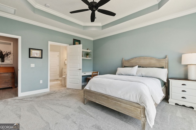 carpeted bedroom with ensuite bath, baseboards, a raised ceiling, and crown molding