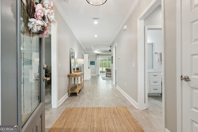 foyer featuring baseboards, light wood finished floors, visible vents, and crown molding