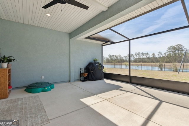 unfurnished sunroom with a ceiling fan and a water view