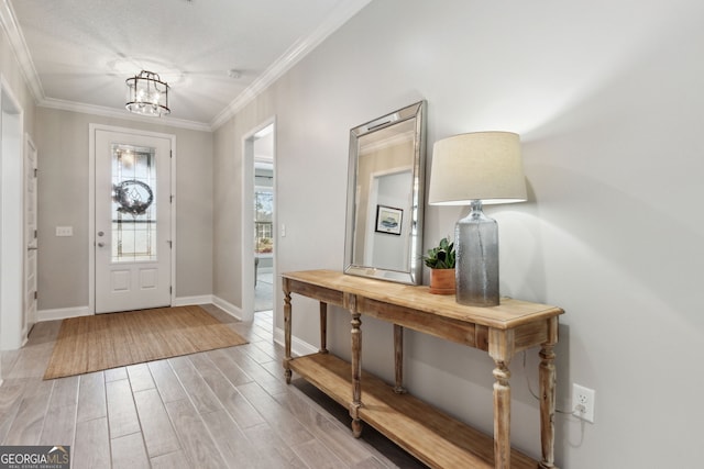 entryway with ornamental molding, light wood-type flooring, baseboards, and an inviting chandelier