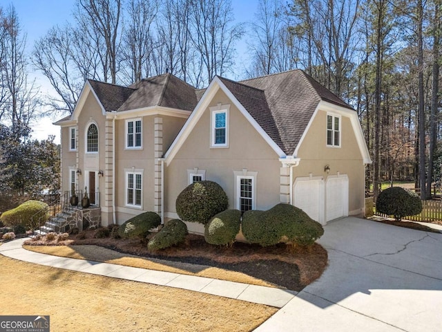 view of front facade with driveway, a shingled roof, an attached garage, and stucco siding