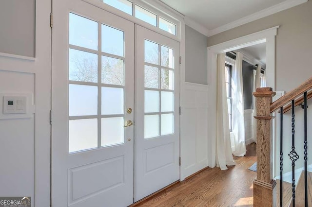 entryway with french doors, stairway, wainscoting, light wood finished floors, and crown molding