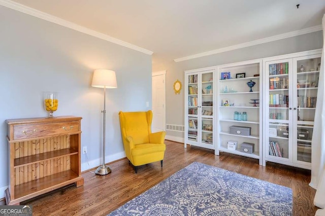 sitting room featuring baseboards, visible vents, ornamental molding, and wood finished floors