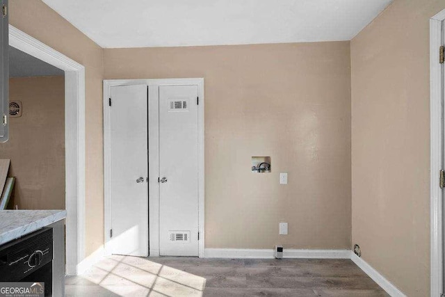 laundry area featuring hookup for a washing machine, visible vents, light wood-type flooring, laundry area, and baseboards