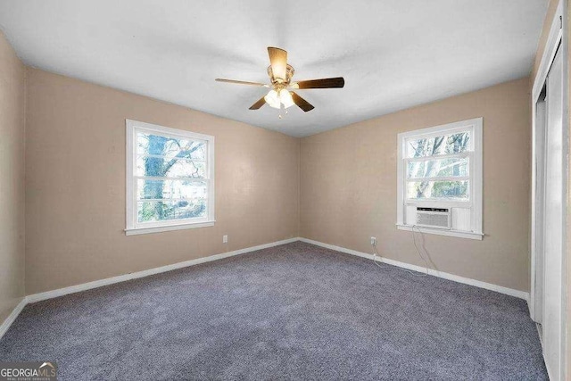 carpeted empty room featuring a ceiling fan, plenty of natural light, baseboards, and cooling unit