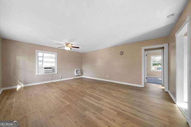 unfurnished living room featuring cooling unit, a ceiling fan, baseboards, heating unit, and light wood finished floors