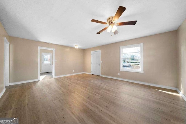 empty room with ceiling fan, baseboards, and wood finished floors