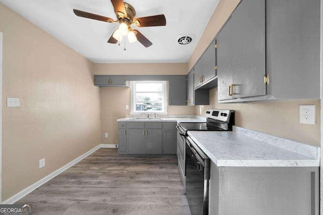 kitchen with light wood-style floors, stainless steel electric stove, gray cabinets, and a sink