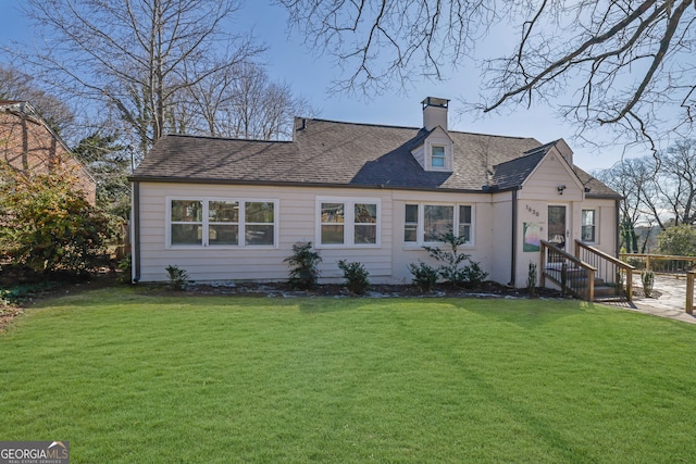 view of front of house featuring roof with shingles, a front lawn, and a chimney