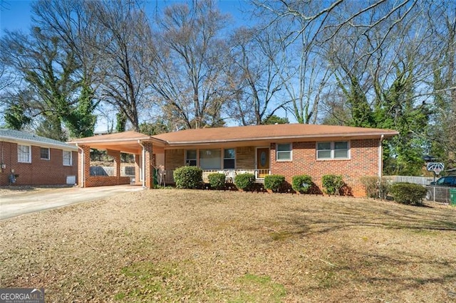 single story home with an attached carport, brick siding, fence, concrete driveway, and a front lawn