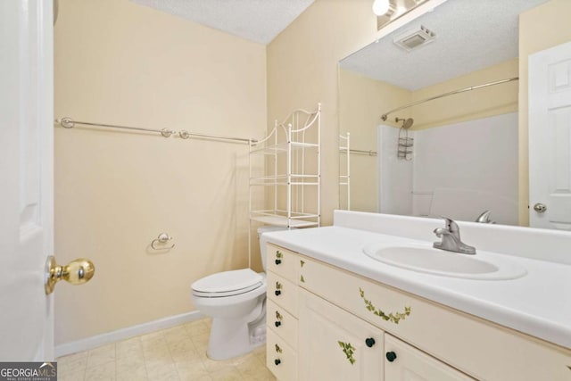 bathroom with toilet, vanity, a textured ceiling, baseboards, and walk in shower