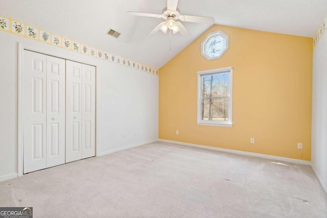 unfurnished bedroom featuring vaulted ceiling, carpet, and visible vents