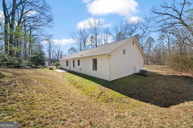 view of side of home featuring cooling unit and a lawn