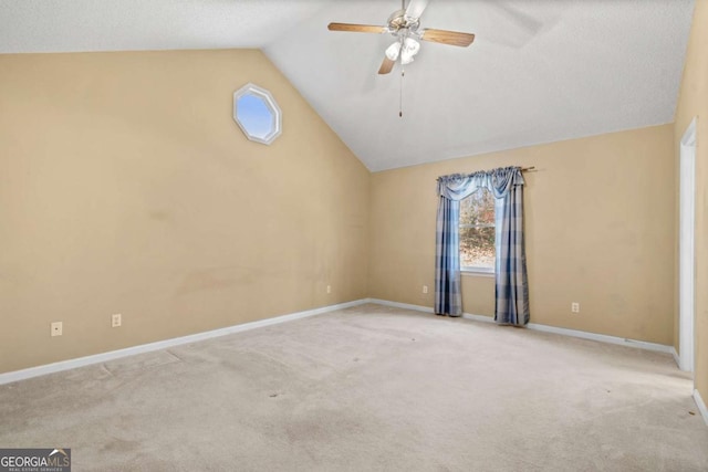 carpeted empty room with ceiling fan, high vaulted ceiling, and baseboards