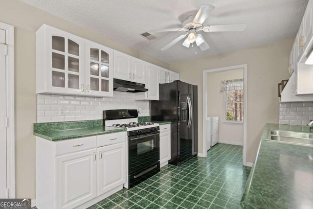 kitchen with gas range oven, black fridge with ice dispenser, a sink, independent washer and dryer, and under cabinet range hood