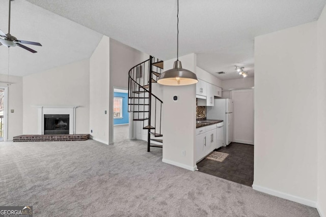 kitchen with dark colored carpet, freestanding refrigerator, plenty of natural light, and white cabinetry