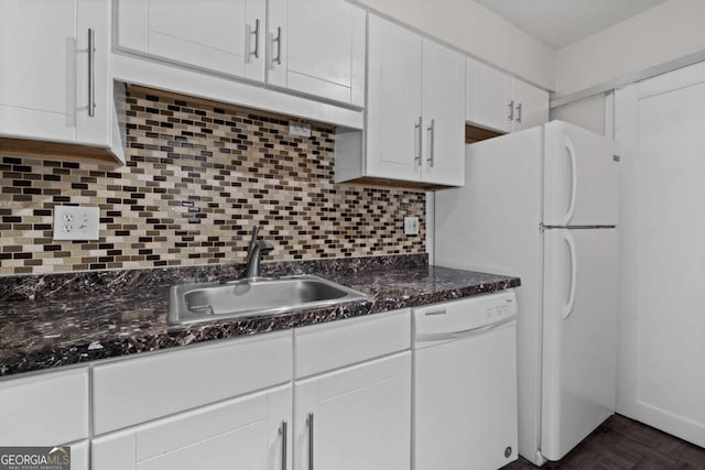 kitchen featuring tasteful backsplash, white cabinets, dark stone countertops, white dishwasher, and a sink