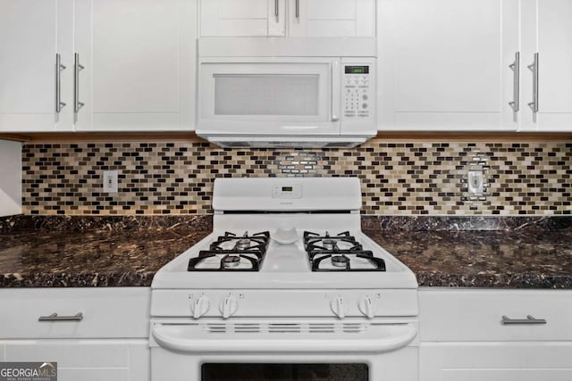 kitchen with white appliances, dark countertops, decorative backsplash, and white cabinets