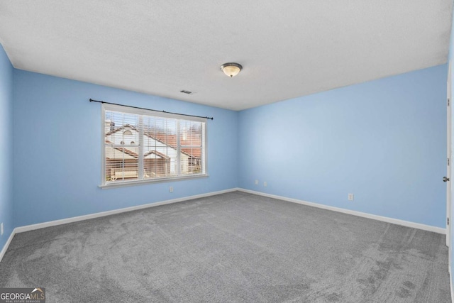 empty room with baseboards, a textured ceiling, visible vents, and carpet flooring