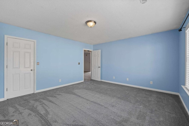 carpeted empty room with a textured ceiling and baseboards