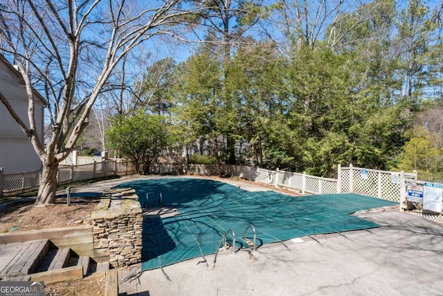 community pool with a patio area and fence