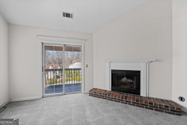 unfurnished living room with a textured ceiling, a fireplace, visible vents, baseboards, and carpet