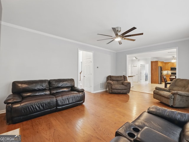 living room featuring light wood-type flooring, visible vents, ornamental molding, and ceiling fan