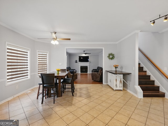 dining room featuring a fireplace, ornamental molding, light tile patterned flooring, baseboards, and stairs