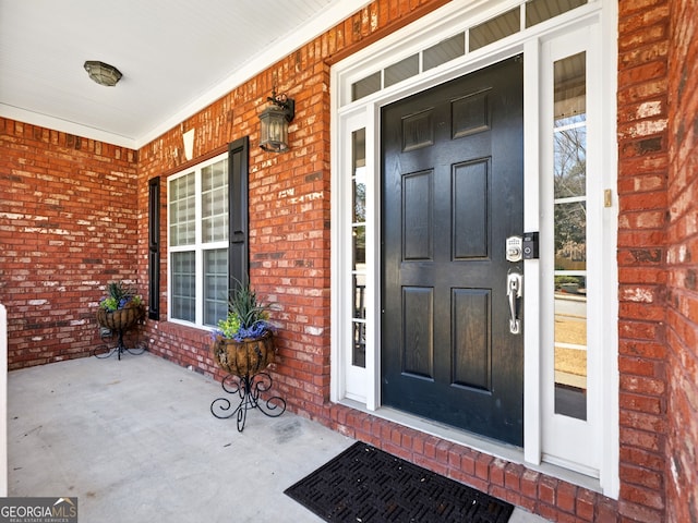 doorway to property with a porch and brick siding