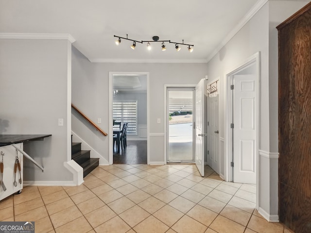 foyer with light tile patterned floors, baseboards, ornamental molding, stairway, and rail lighting