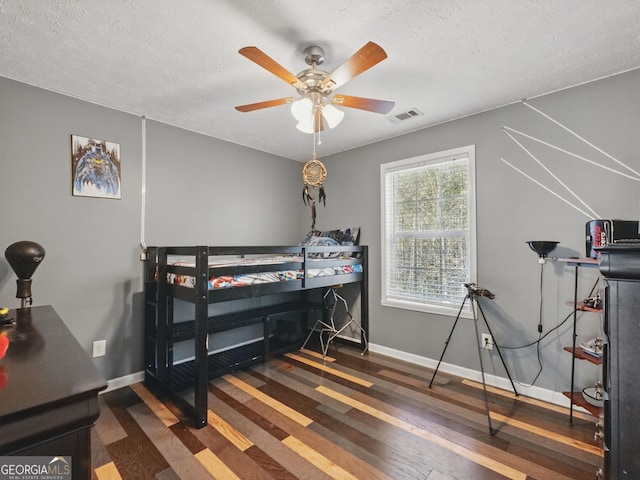 bedroom with a textured ceiling, wood finished floors, and baseboards