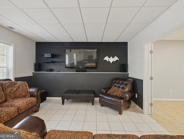 tiled living area featuring a drop ceiling and visible vents