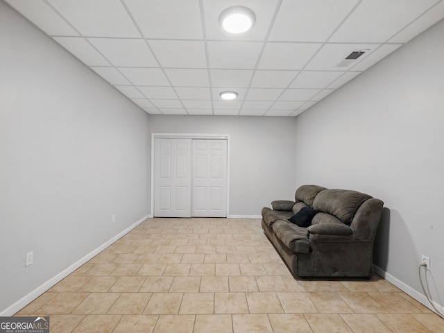 living area with visible vents, baseboards, and a drop ceiling